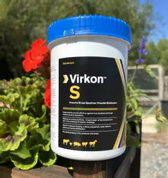 Lanxess Virkon S Disinfectant Powder 1kg tub in the sun next to some flowers