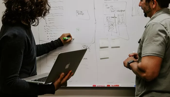 Two colleagues mapping out a website plan on a whiteboard