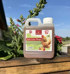 A 1 litre bottle of apple cider vinegar next to some flowers