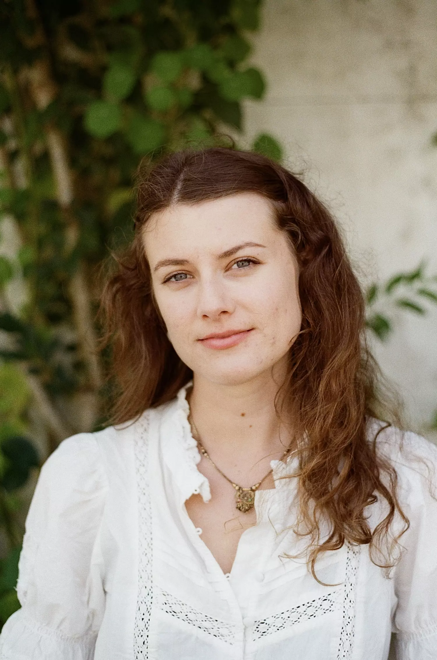 Portrait photo of a female sat in front of a foliage wall