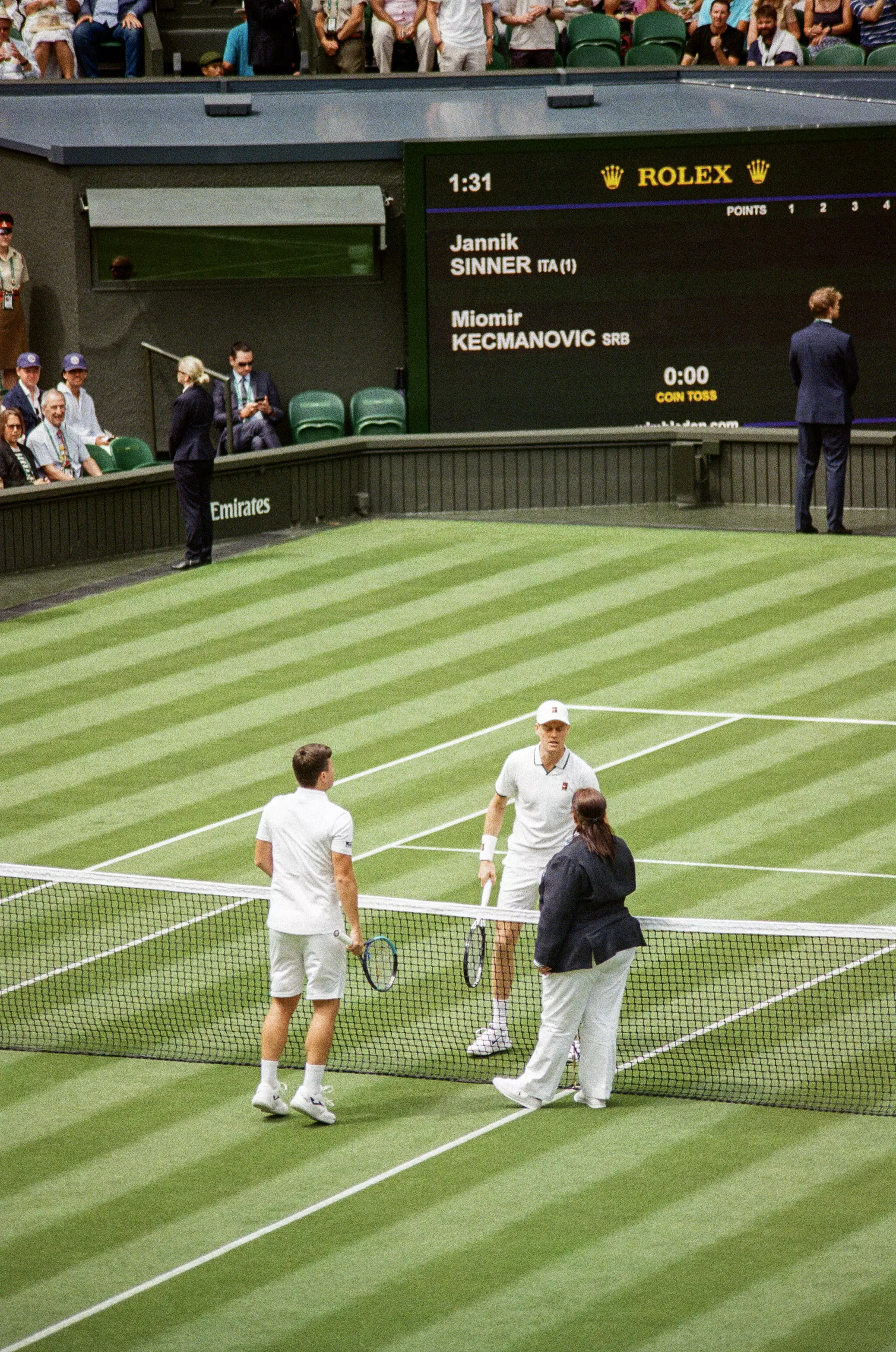 Jannik Sinner and Miomir Kecmanovic stand at the net with the Umpire on Centre Court, Wimbledon