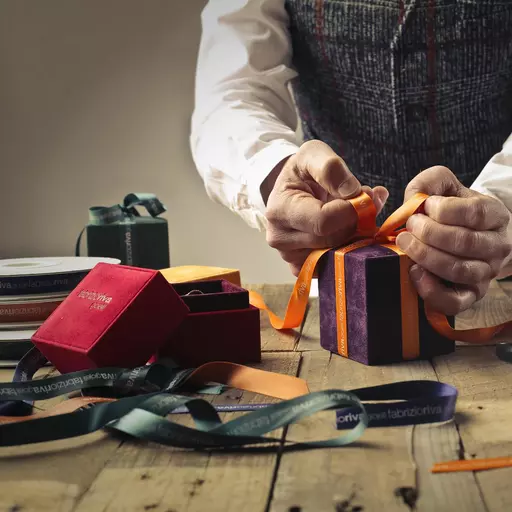 Person Tying Ribbon on Purple Gift Box