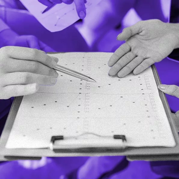 Group of hands holding a clipboard with assessment results and pointing at a graph