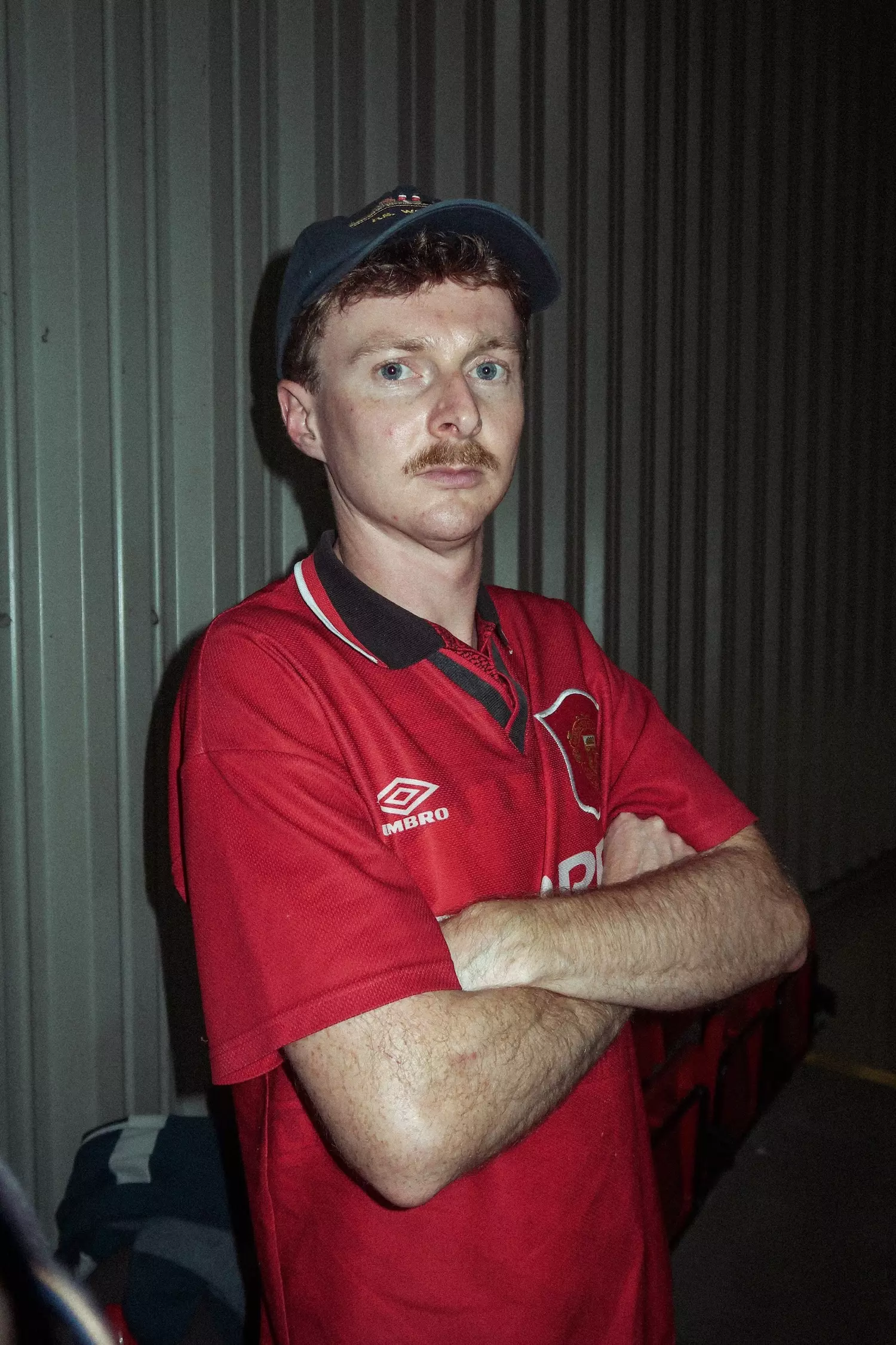 Mid shot of a male looking serious to camera with a red Manchester United shirt on
