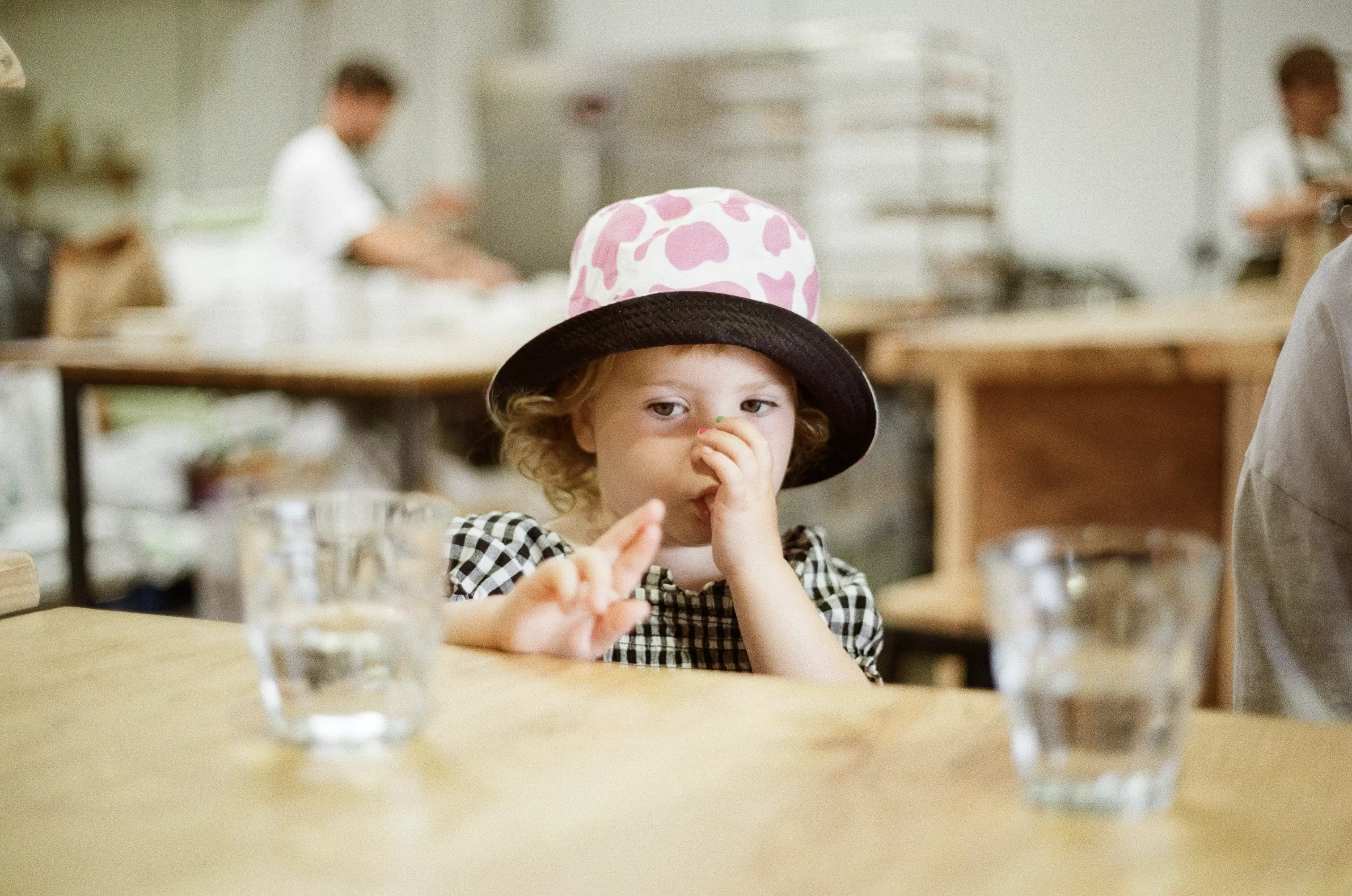Mid shot of a young girl sat at high table and sucking her thumb