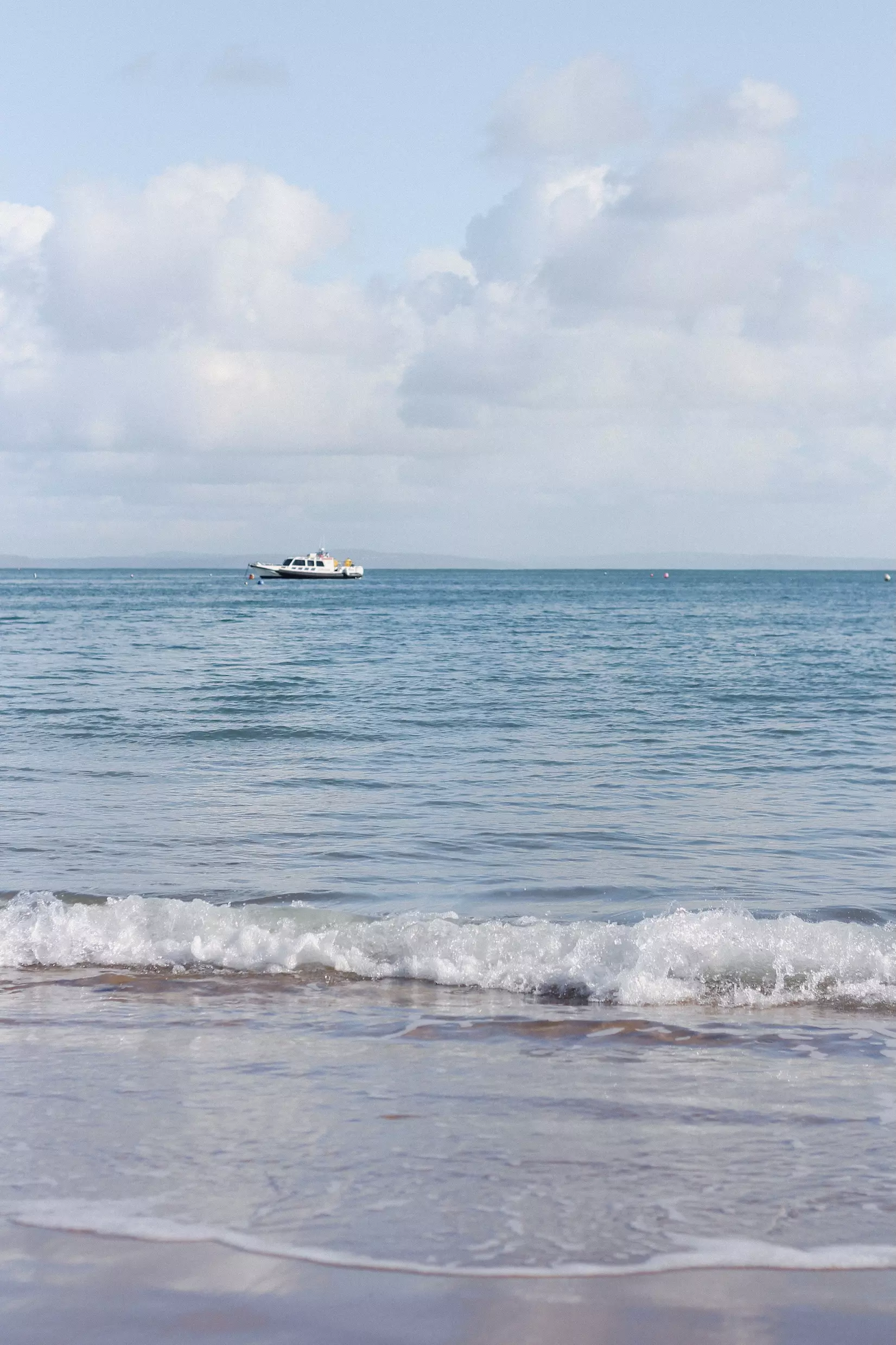 View of the sea on Tenby beach and a boat in the distance