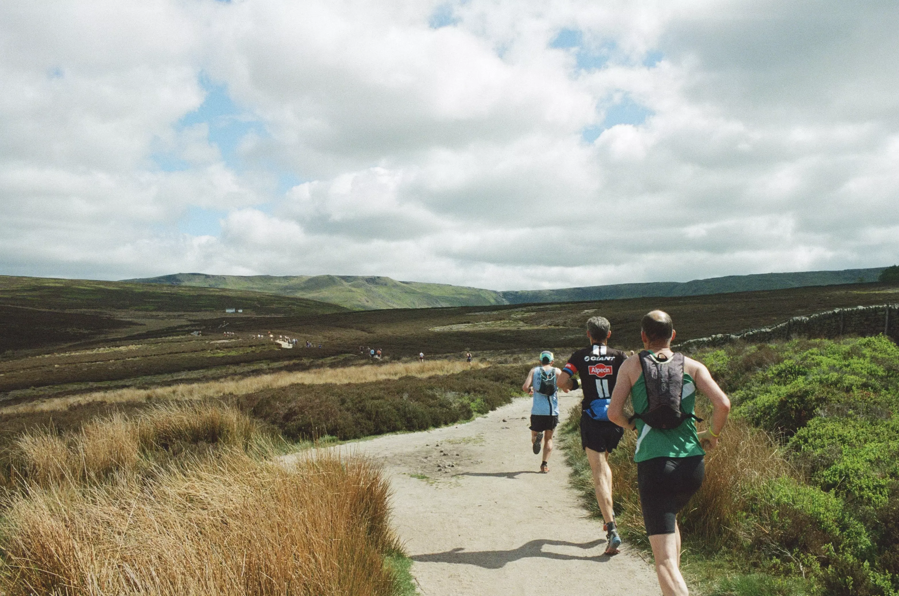Landscape shot of Kinder Downfall and fellrunners passing by