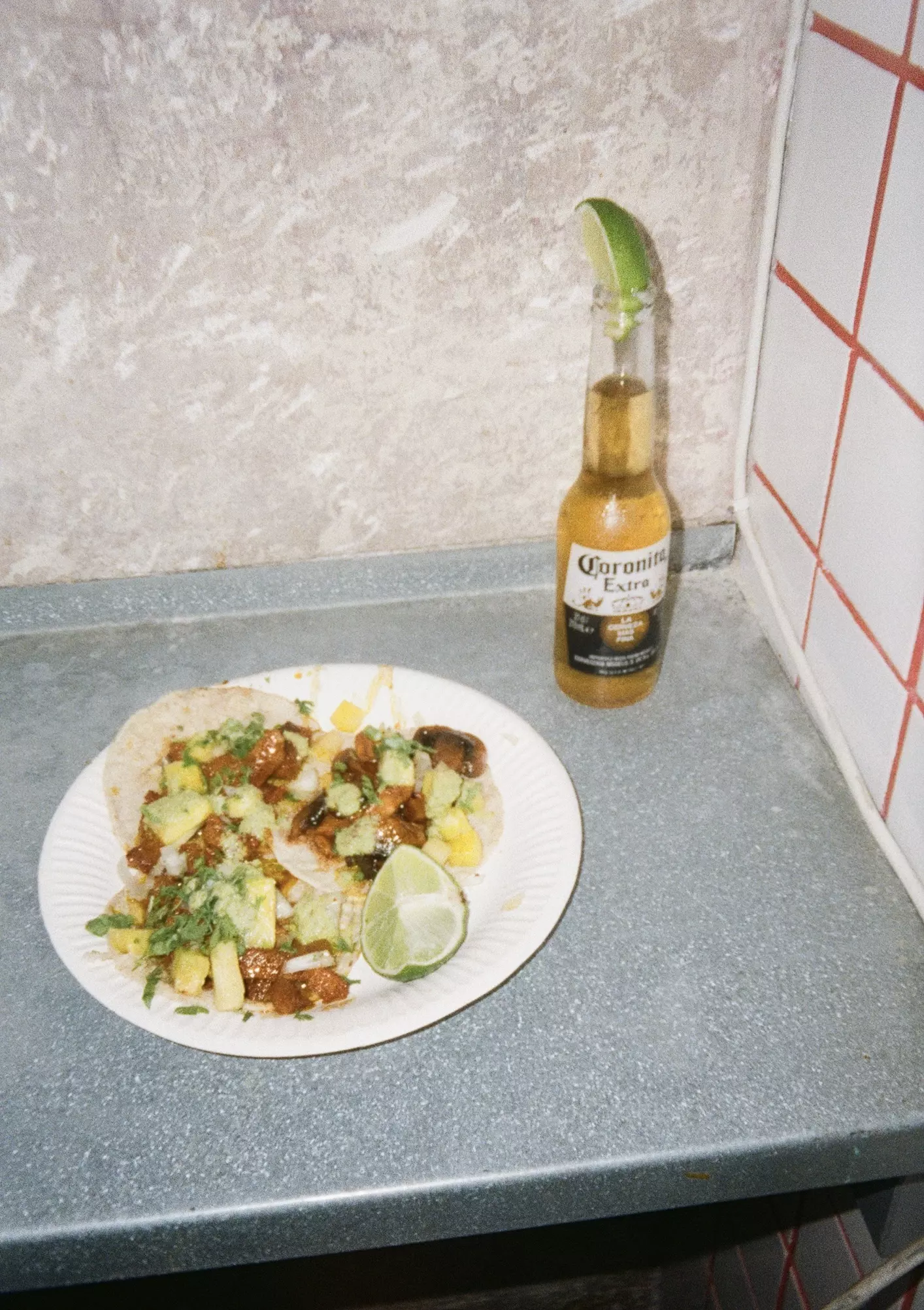 Flash photo of three taco on a plate and a bottle of peroni