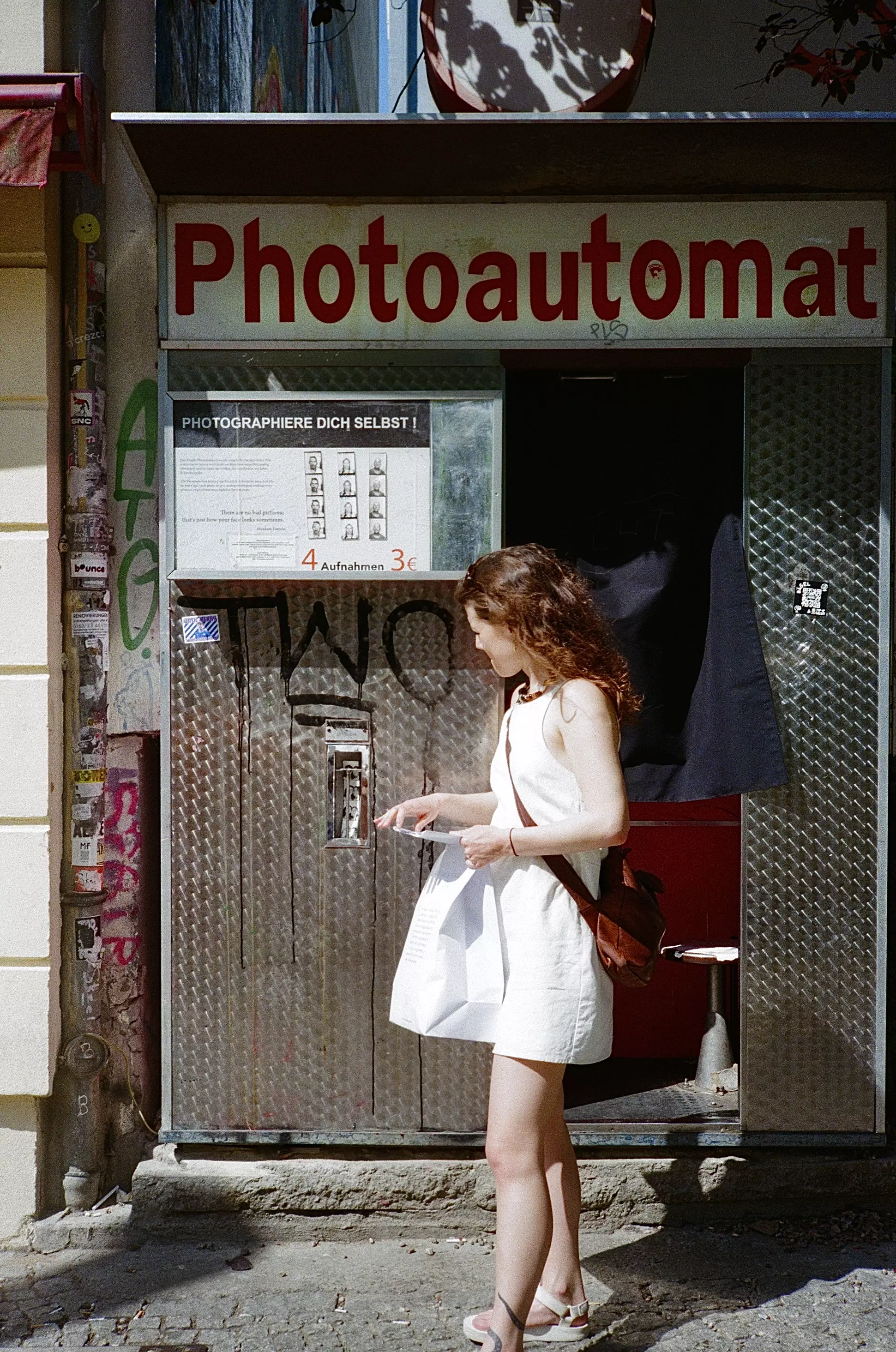 Young female walking in front of a vintage Photoautomat in the Berlin streets