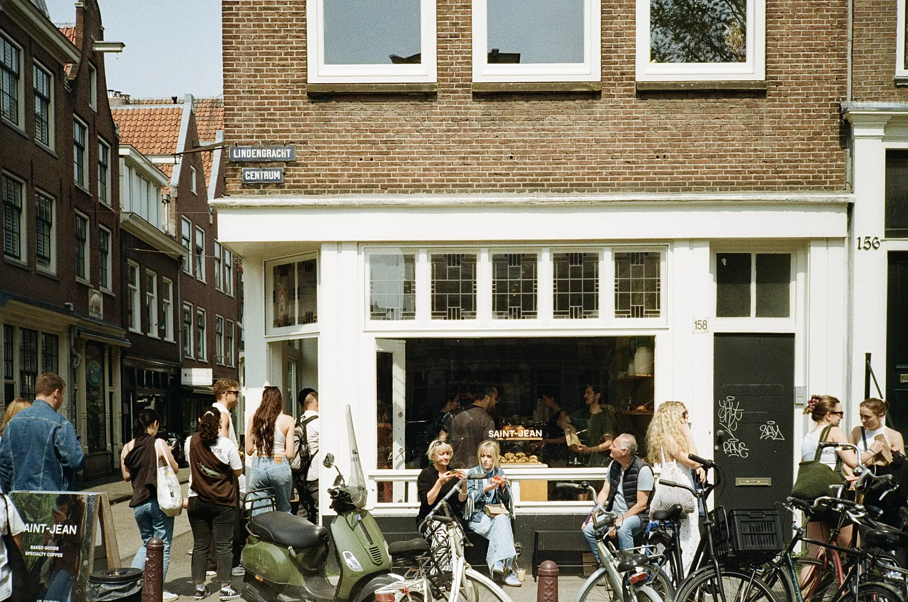 Exterior shot of Saint Jean bakery in Amsterdam with people sat outside and queuing