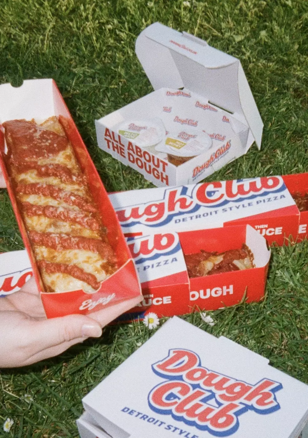 Dough Club Pizza packaging set against a white tiled wall