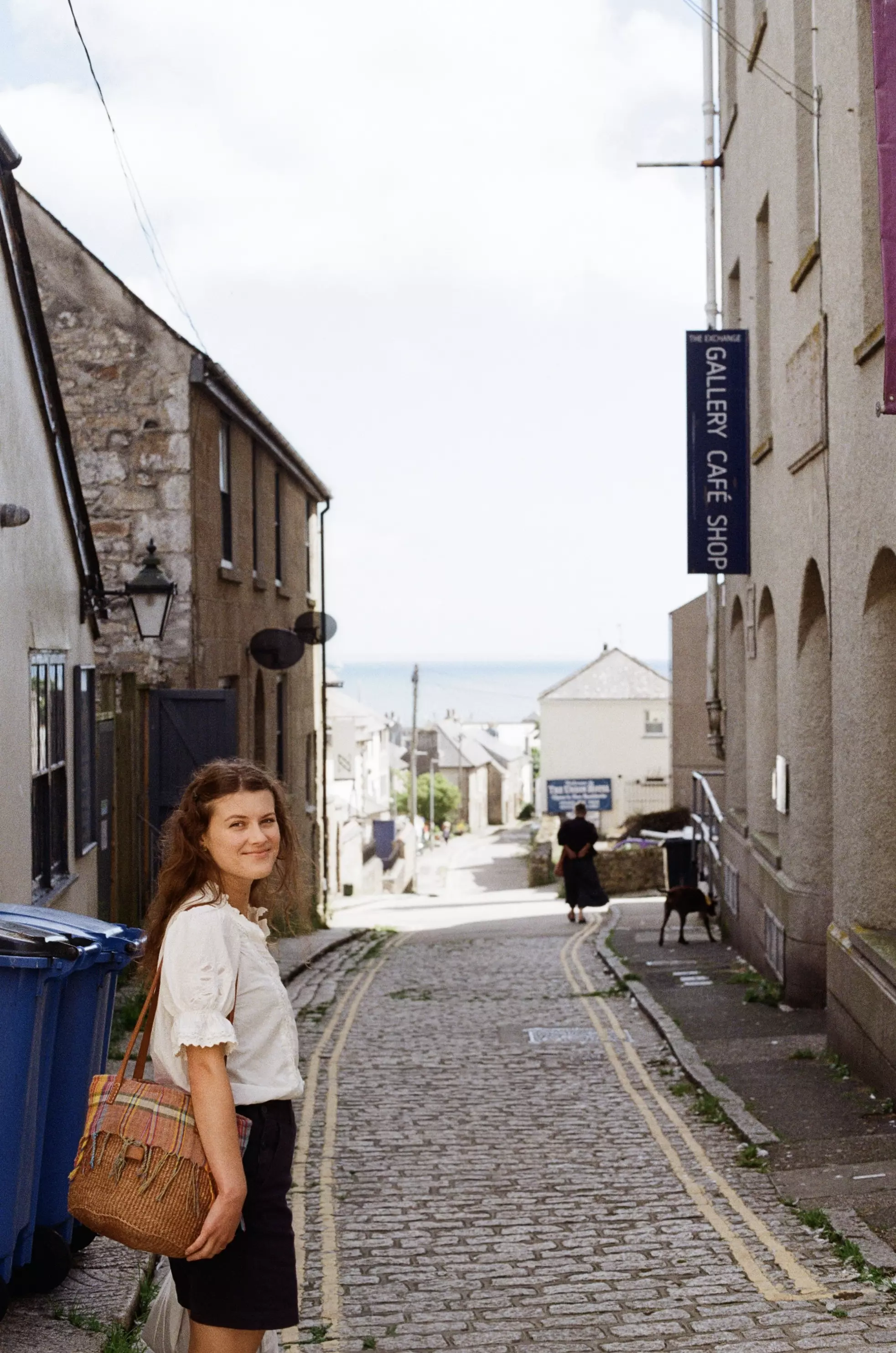 A girl facing camera standing in front of a street to the sea